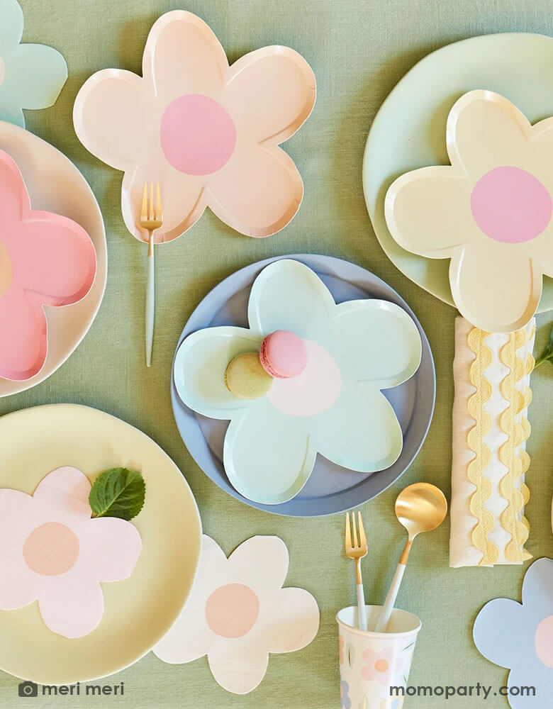 A spring party table featuring Momopartys's daisy shaped plates and napkins in multiple pastel colors, with pastel colored round table, it makes a charming tablescape for a spring gathering, kid's daisy themed birthday or an Easter celebration.