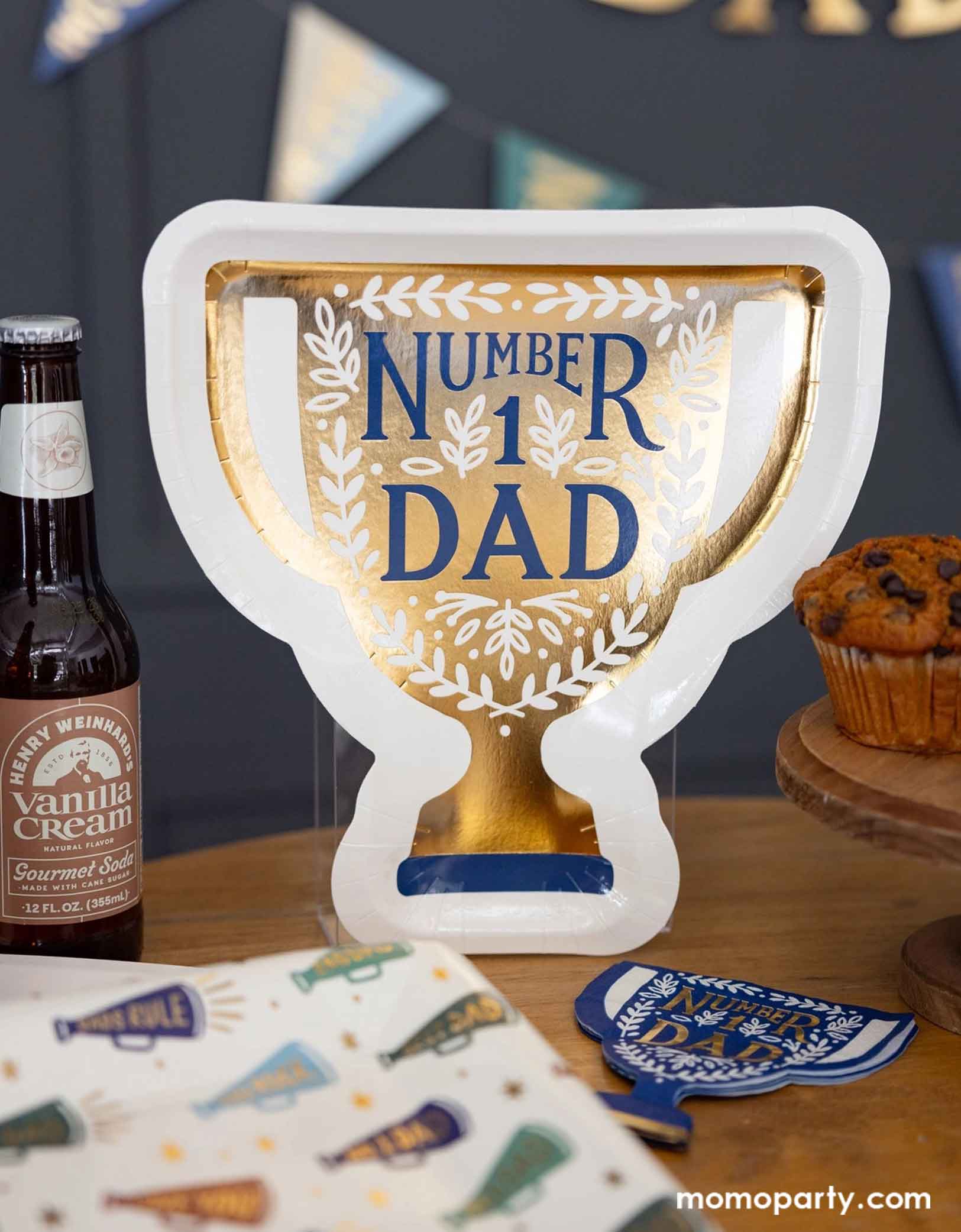 A Father's Day celebration party table featuring Momopartys's Father's Day party supplies including the 10" x 10.5" Number 1 Dad Trophy Plates & matching napkins, and megaphone patterned dinner plates, some beers & muffins. Behind the table there's a Happy Father's Day banner with pennants hung on the navy wall, making this a perfect scene for a fun and playful Father's Day celebration!
Perfect for a Father's Day celebration,
