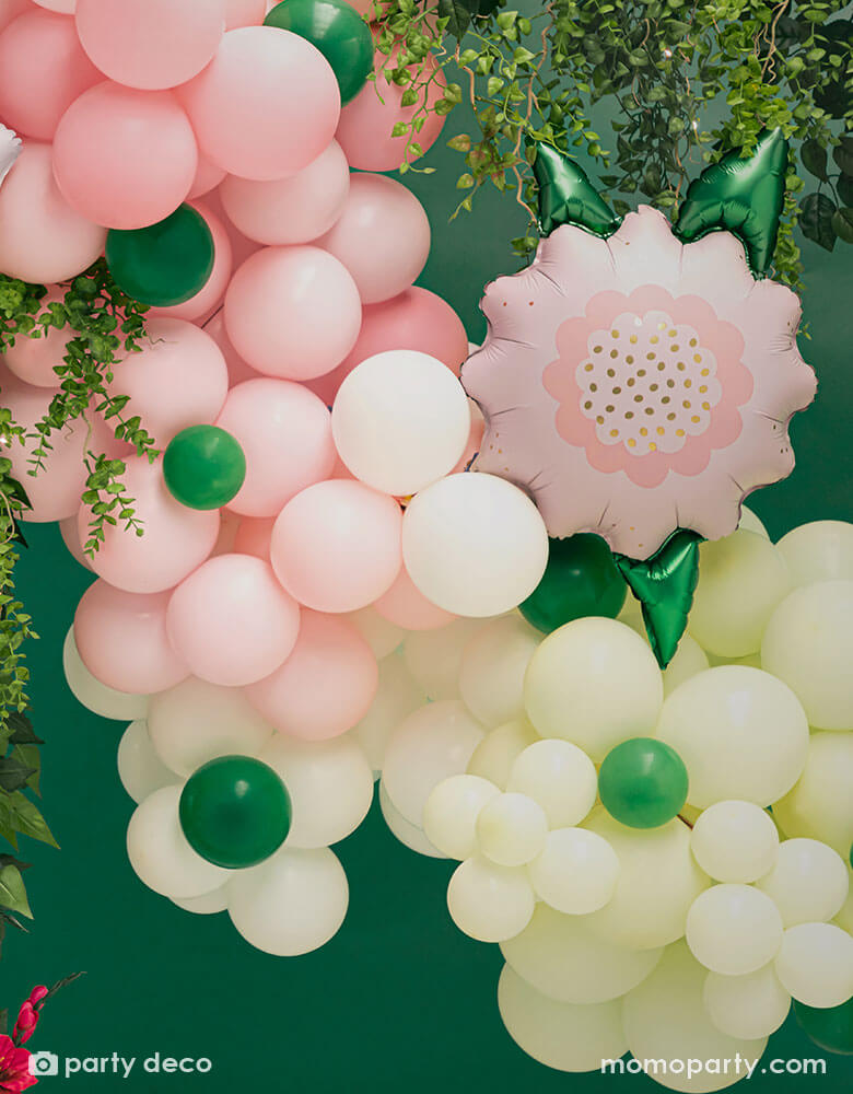 A spring inspired balloon garland in pastel yellow and pink colors peppered with some small emerald green as the green foliage adorned with Momopartys's 23" x 19" pink flower foil balloon, makes this a great balloon decoration for a garden party or spring inspired celebration.
