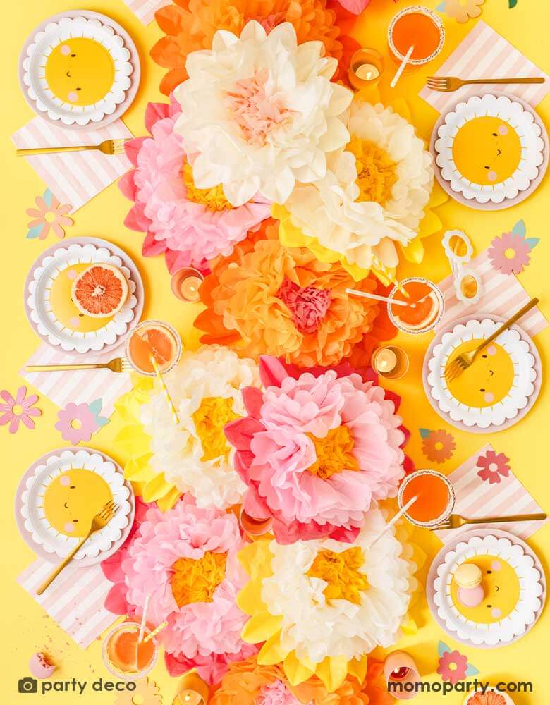 A cheerful "Flower Power" themed table decoration features Momopartys's sunflower sunny scallop edged round plates, pink and white striped large napkins and cream and pink tissue paper flower decorations in the middle as centerpiece. Around the table you can see some flower paper cutouts scattered as decorations, with some macarons, sweet desserts, grapefruits and juice, this makes a great idea for kid's "You're my sunshine" themed party or any "Good Vibes" themed celebration!