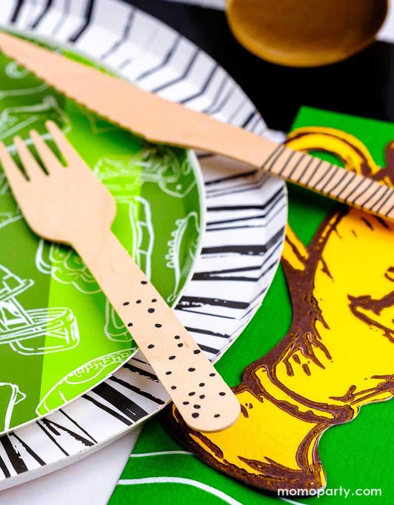 A closer look of a modern yet festive football party tablescape featuring football themed tableware from Momopartys including the football shaped paper placemat, the touchdown dessert plates, the trophy shaped napkins on a black striped table runner, making this a perfect inpo for a kid's football themed birthday party or a Superbowl party table decoration.