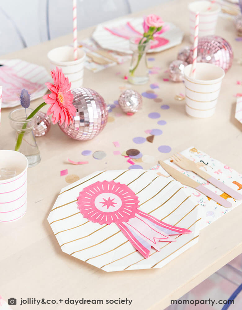 A girly pony themed party table feature Momopartys's show ribbon shaped napkins, gold striped party plates, pink striped party cups and cowgirl motif large napkins by Daydream Society. In the middle of the party table, there are some pink disco balls as the centerpiece which are with purple, pink and gold confetti spread out the table, making this an adorable inspiration for girl's derby, pony themed birthday party.