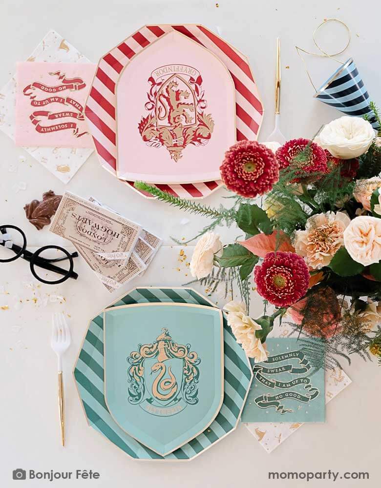 A beautiful and elegant Harry Potter themed party tablescape features Momopartys's Harry Potter house pride shield-shaped 7" side plates with Slytherin and Gryffindor logos and colors paired with 10.25 striped dinner plates. Next to the plates are Harry Potter motif large napkins in gold foil and matching small napkins from Momopartys. On the table there's a pair a Harry Potter's glasses, a Jelly Belly Chocolate Frog, tickets to Hogwarts and a beautiful flower arrangement. A magical party for kids!