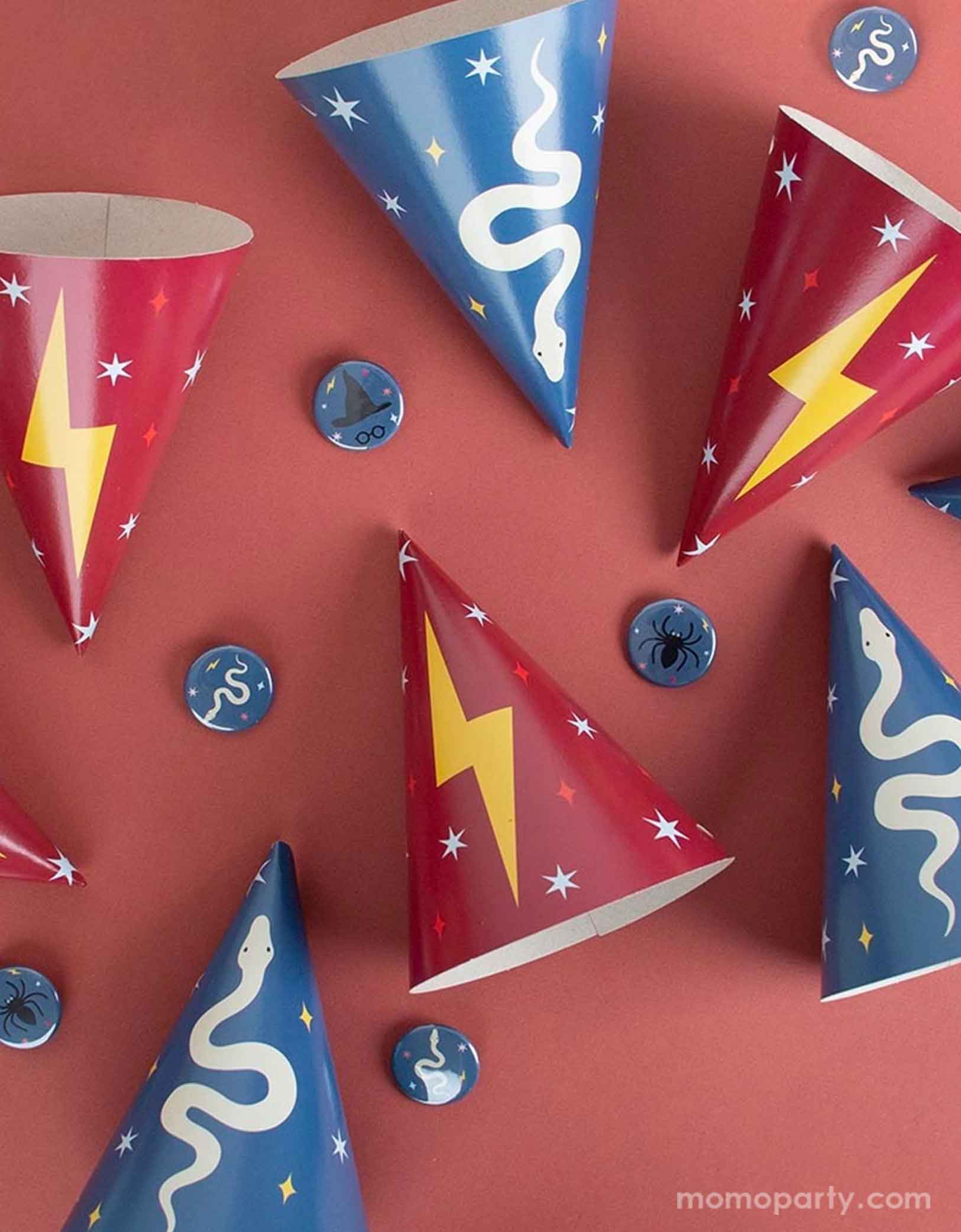 A overhead shot of a red party table featuring Momopartys's Wizard Party Hats by My Little Day. In the classic wizard colors of red and navy blue with designs of a lightning bolt and snake, this set of 8 wizard hats that is suitable for either a Harry Potter themed birthday or a Halloween celebration.
