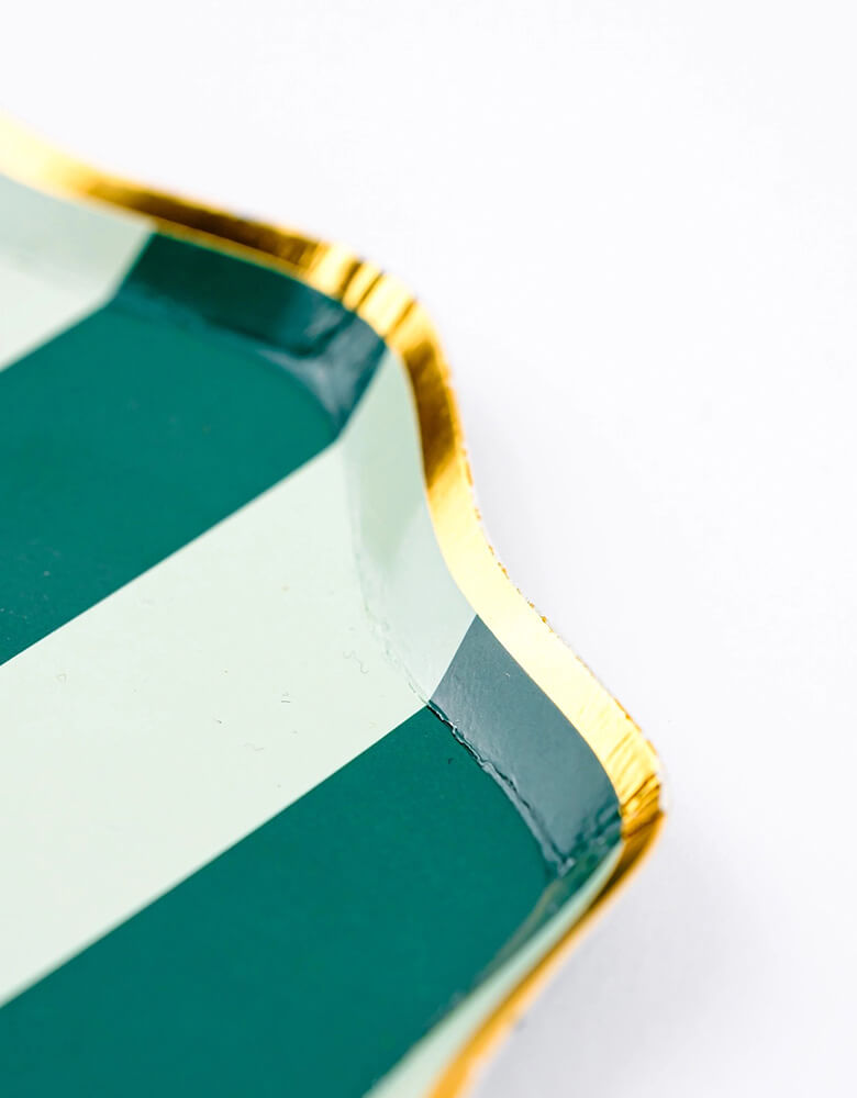 A close up shot of Momopartys's 8.5" Holiday Stripes Dessert Paper Plates by Gatherings. Comes in a set of 8 plates, made with eco-friendly FSC Mix paper, these vibrant and stylish plates with gold foil edge are the perfect addition to any holiday table, and their durable design ensures they can handle any dessert or appetizer. Make your holiday celebrations even more special with these delightful plates!