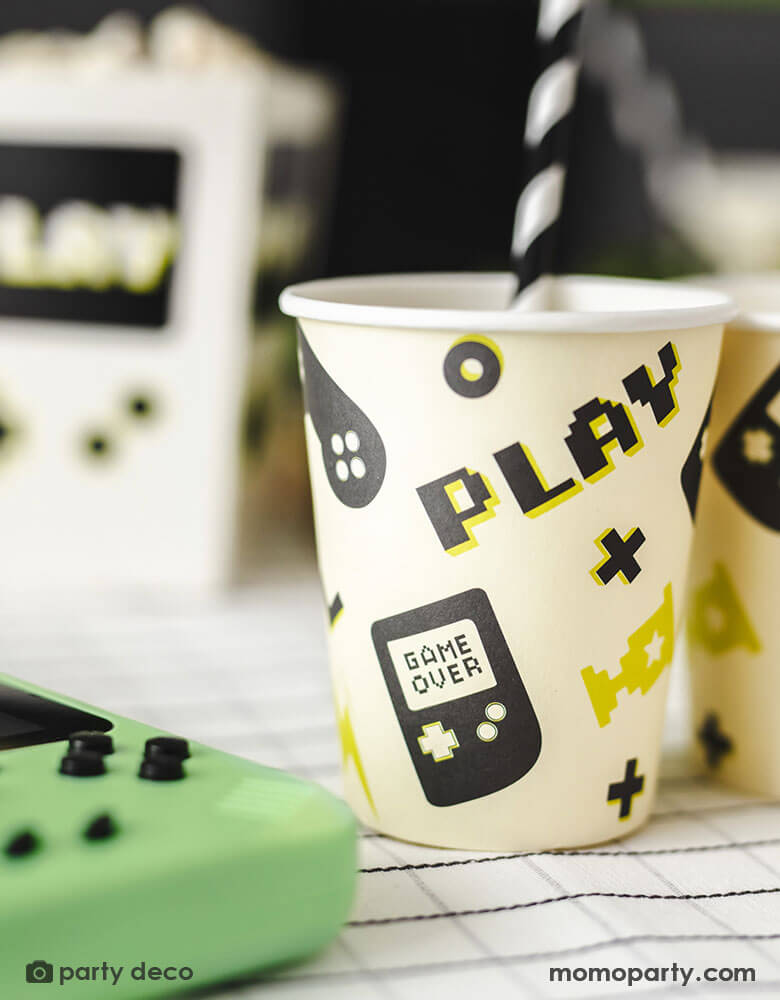 A close up shot of Momopartys's 7.4 oz Video Game Party Cups by Party Deco. Designed with a game device motif pattern with SUPD labelling. pixelated word "PLAY" on it, this set of 6 party cups is perfect for any gamer.