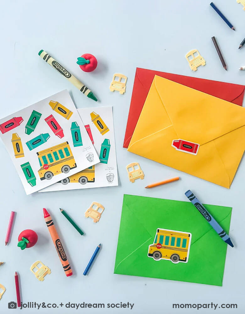 A table filled with school supplies and envelopes and Momopartys's school days sticker set featuring school bus shaped and crayon shaped stickers in bright colors. This sticker set is perfect to get your little one excited for the first day of school!! Use to decorate notebooks, classroom favors or teacher gifts. Plus they're perfect for decorating presents or used as party favors.