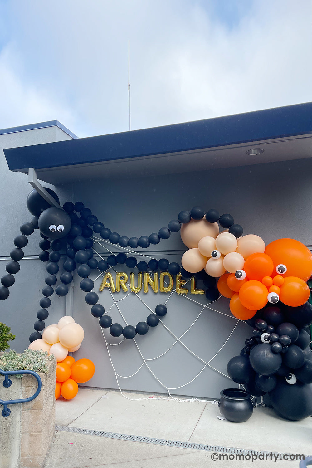 Halloween Balloon garland wall decoration by Momopartys. Featuring a giant spider balloon made with two jumbo 3 ft Qualatex balloons and link balloons as the legs. On the right there's a 12 ft balloon garland in the colors of black, orange and blush in multiple sizes with 5" mini eyeball balloons adorned, it sets a spooky yet adorable scene for a kid's Halloween party or a trick-or-treat celebration!