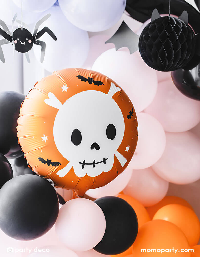 A festive Halloween party balloon set up featuring Momopartys's 14" orange round skull foil balloon by Party Deco. A festive orange skull with cute details is the perfect addition to a not-so-spooky kid's Halloween party! In the back of the skull foil balloon there is a balloon garland in black, orange, pink and purple colors, around the balloon garland, some paper spider and bat honeycomb decorations are topped to create a spooky yet adorable vibe to a fun kid's Halloween bash.