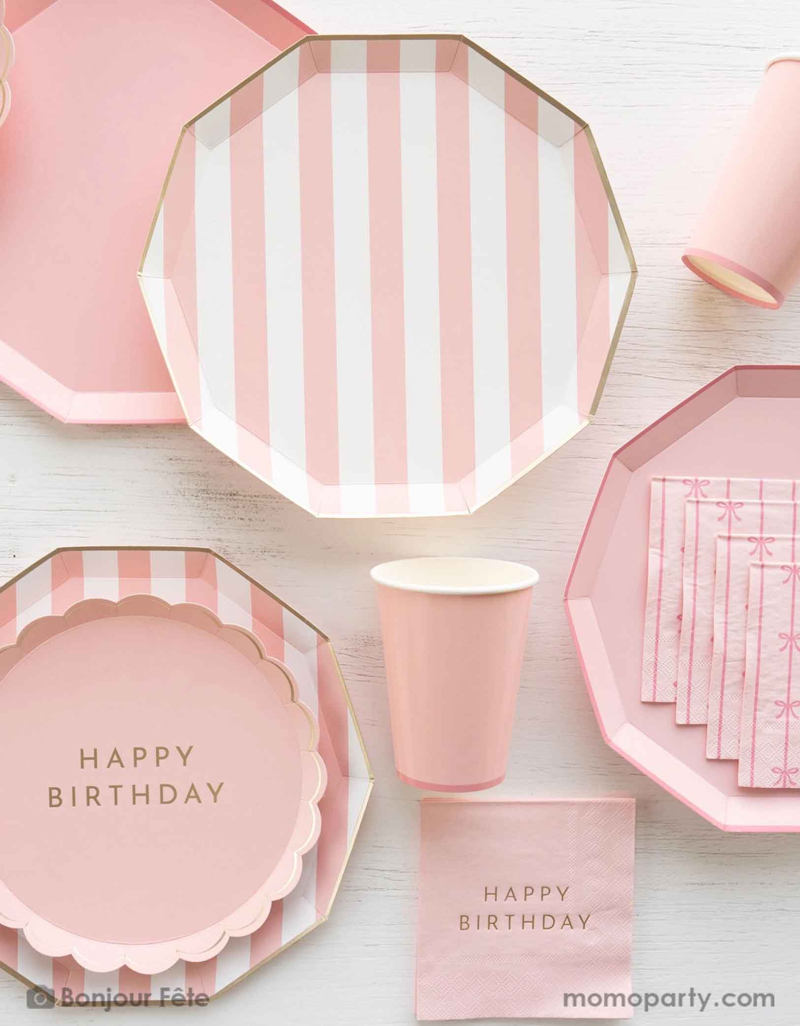 An overhead shot of a party table filled with Momopartys's pastel pink themed party tableware including pastel pink cabana striped dinner plates and pastel pink dinner plates in decagon shape with matching party cups, with the pink scalloped round plate with Happy Birthday on it - a great party collection for girl's birthday celebration.