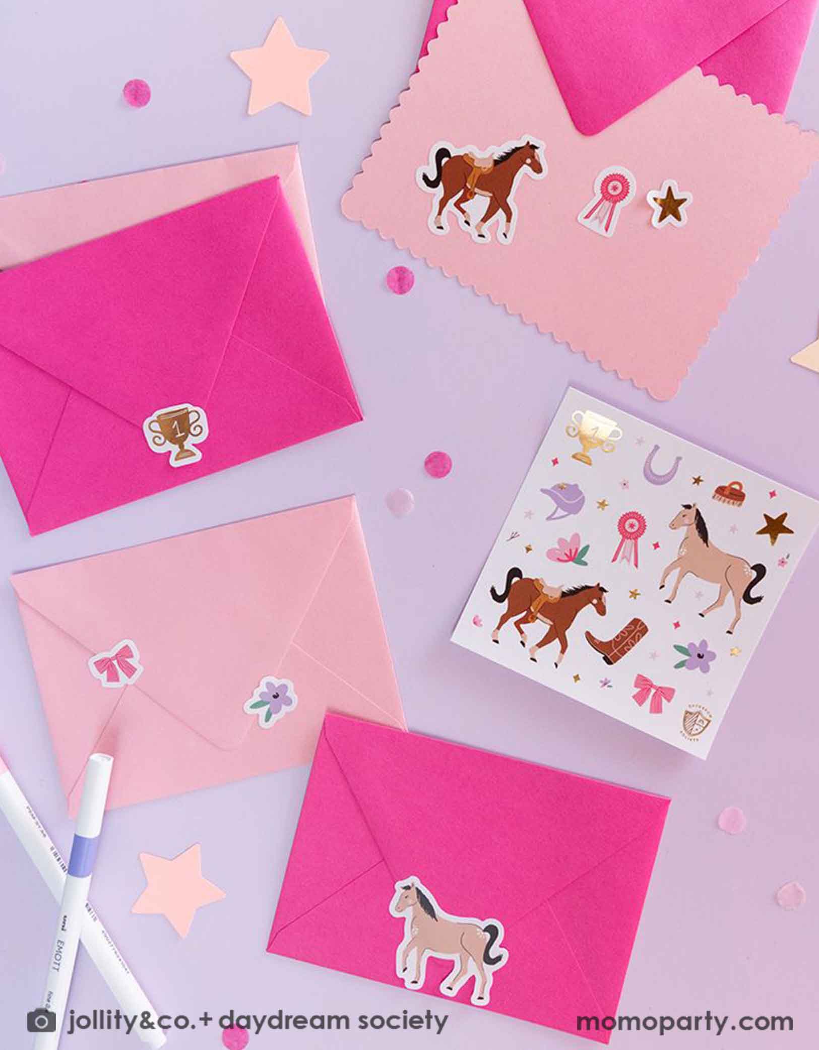 A few pink envelopes decorated with Momopartys's Pony Tales Sticker Set by Daydream Society. This sticker set comes in a set of 4 sheets, including images of horses, ribbons, florals and bows! They make the perfect birthday invitations or gift for every pony lover. Around the envelopes are some pink confetti, some star shaped paper decorations and pens.