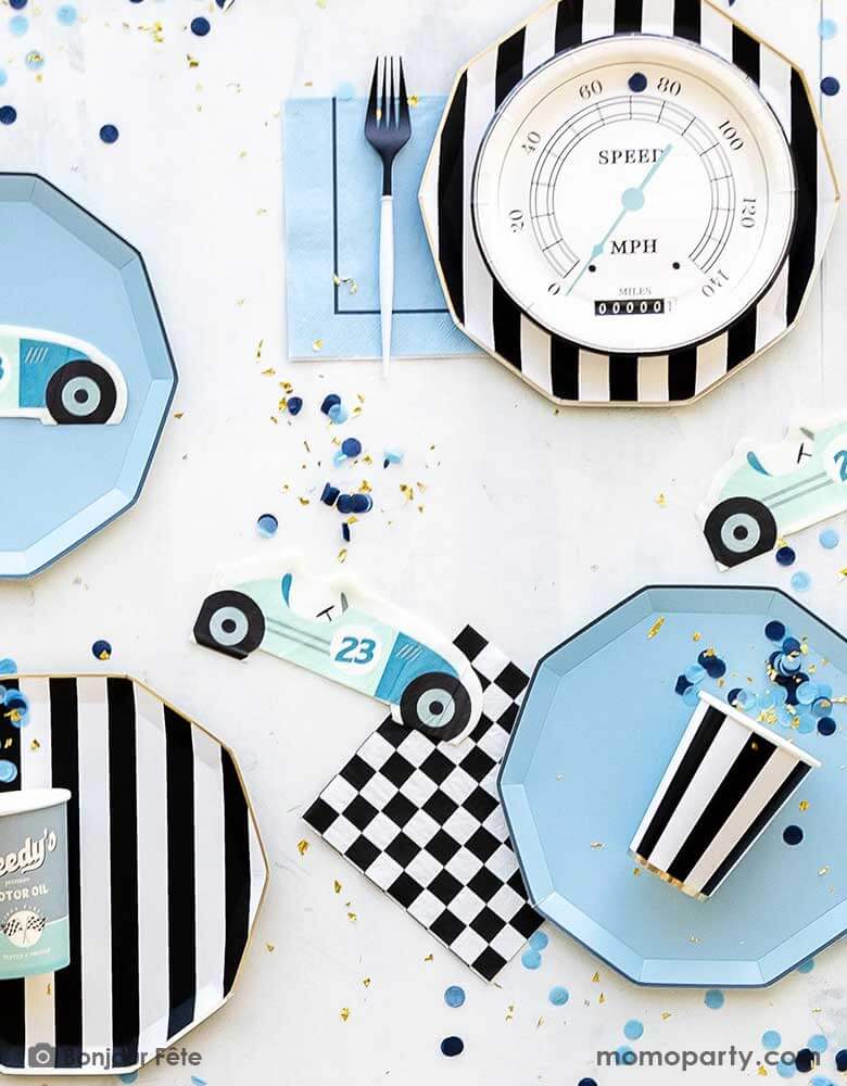A baby blue, black and white themed race car party table features Momopartys's race car themed and basic themed party supplies including the sky blue dinner plates, the black and white striped dinner plates and party cups, checkered napkins, Miles per Hour speedometer shaped plates, and race car shaped napkins. Along with blue confetti spread around, this makes a modern yet playful tablescape for boy's car themed birthday celebration.