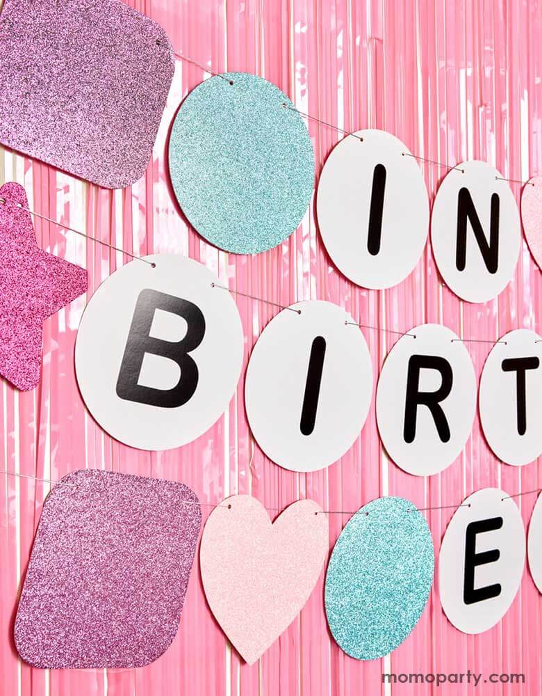 A closeup shot of Momopartys's 5' Taylor Swift In My Birthday Era friendship bracelet inspired birthday party banner by Xo, Fetti hung on a iridescent fringe curtain decoration. Made with paper with glittered pennants in purple, pink and blue, this fun birthday banner is perfect for any Swiftie for their special day!