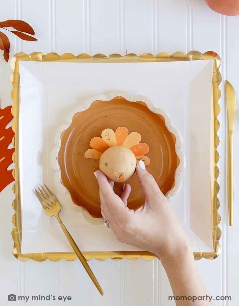 A beautiful and playful Thanksgiving tablescape features Momopartys's Thanksgiving party supplies including fall inspired paper plates, oak leaf shaped napkins and turkey surprise balls. A perfect inspo for a modern Thanksgiving dinner tableset in this harvest season.