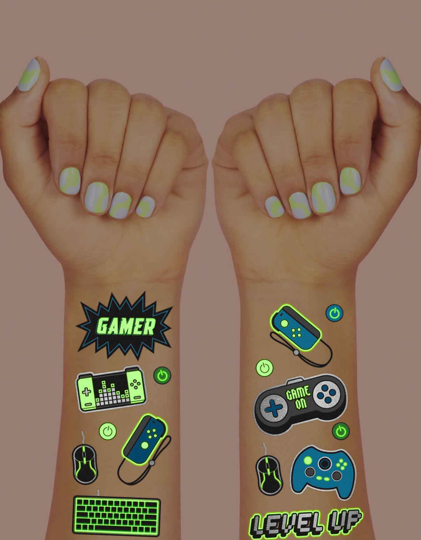 Two arms decorated with Momopartys's Video Gamer Glow in the Dark Kids Temporary Tattoos by xo, Fetti. Comes in a set of 40 tattoos, these glow in the dark video game temporary tattoos are the perfect kids after school activity or a video game themed party accessory! 40 designs including game controllers, game devices, level up, game over signs means no gamer gets left behind - call all the players, its game on!