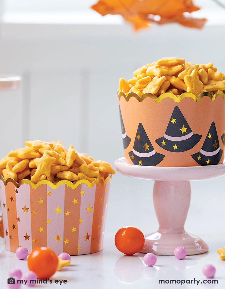 A Halloween party table features Momopartys's Jumbo Witch Hats and Stars Foil Baking Cups by My Mind's Eye. Step up your Halloween party game with these JUMBO foil baking cups featuring witch hats and stars. These 8 oz cups with goldfish, gum balls are perfect for all your spooky treats.
