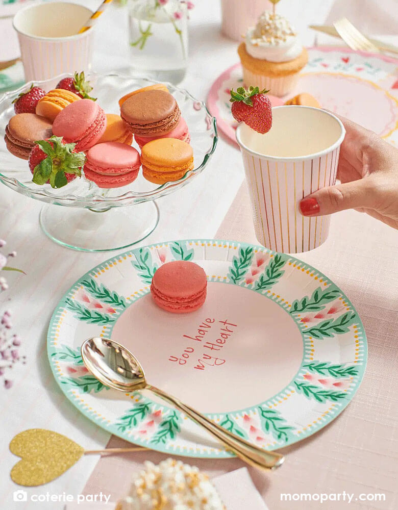 A beautiful love themed party table featuring Momopartys's 9 oz pale pink pinstripe party cups by Coterie Party and 9" All You Need is Love Large Plates with a message of "You have my heart" on the plate. With a tableset with pastel pink themed tableware with heart shaped elements, it's a perfect inspiration for a Valentine's Day celebration.