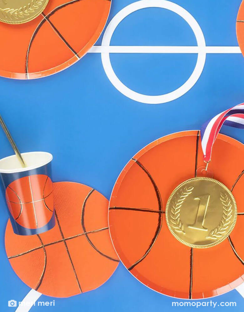 A table set with basketball themed tableware from Momopartys including a 8" basketball shaped plate, 6.5" basketball shaped napkin and a 9 oz basketball party party cup by Meri Meri.