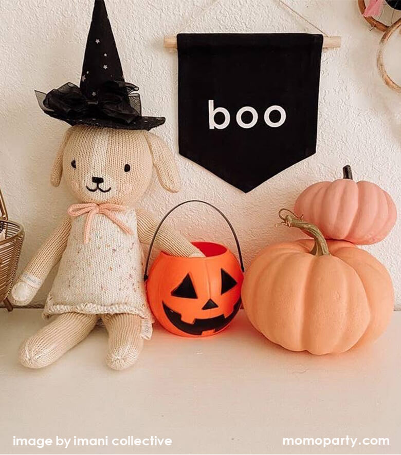 Halloween kid's room decoration with Boo hang Sign and cuddle and kind Mia the dog with a witch head accessory, a pumpkin trick or treat basket, 2 pink pumpkins, from Party Boutique Online at momopartys.shop