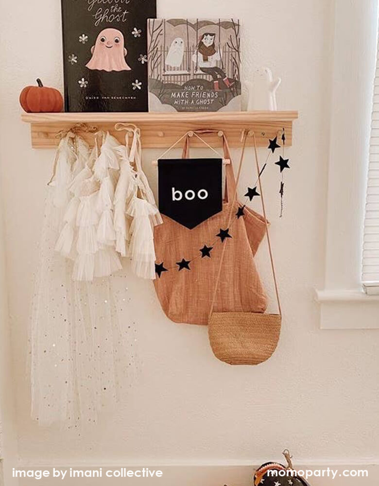 Kid's room wall shelf hanging with girl's beautiful tutu dresses, a black canvas Boo hang Sign, black star banner, Woven bags. And a pumpkinhalloonween books, a cute white ghost figures. These modern unique halloween product are so fun for your little one's room decoration, party decoration, and instagram worthy photos for you halloween celebration memories. Sell from Party Boutique Online at momopartys.shop