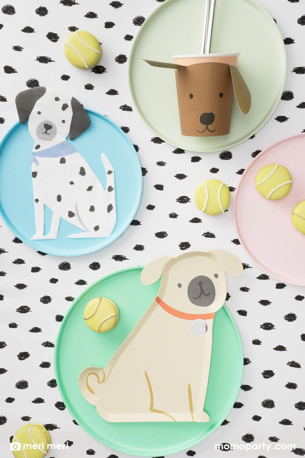 Momopartys kid's puppy dog themed birthday party table flat lay, decorated with Pug Plates on a mint round plate, Brown Puppy Cup with silver foil straws on pistachio colored plate, Puppy Napkins on the light blue round plate, tennis ball macarons all on the black dots tablecloth, These modern and cute design party supplies from Meri Meri of Cat and Dog Collection,will make an Insta-perfect party table for your kid's puppy or dog themed birthday party.