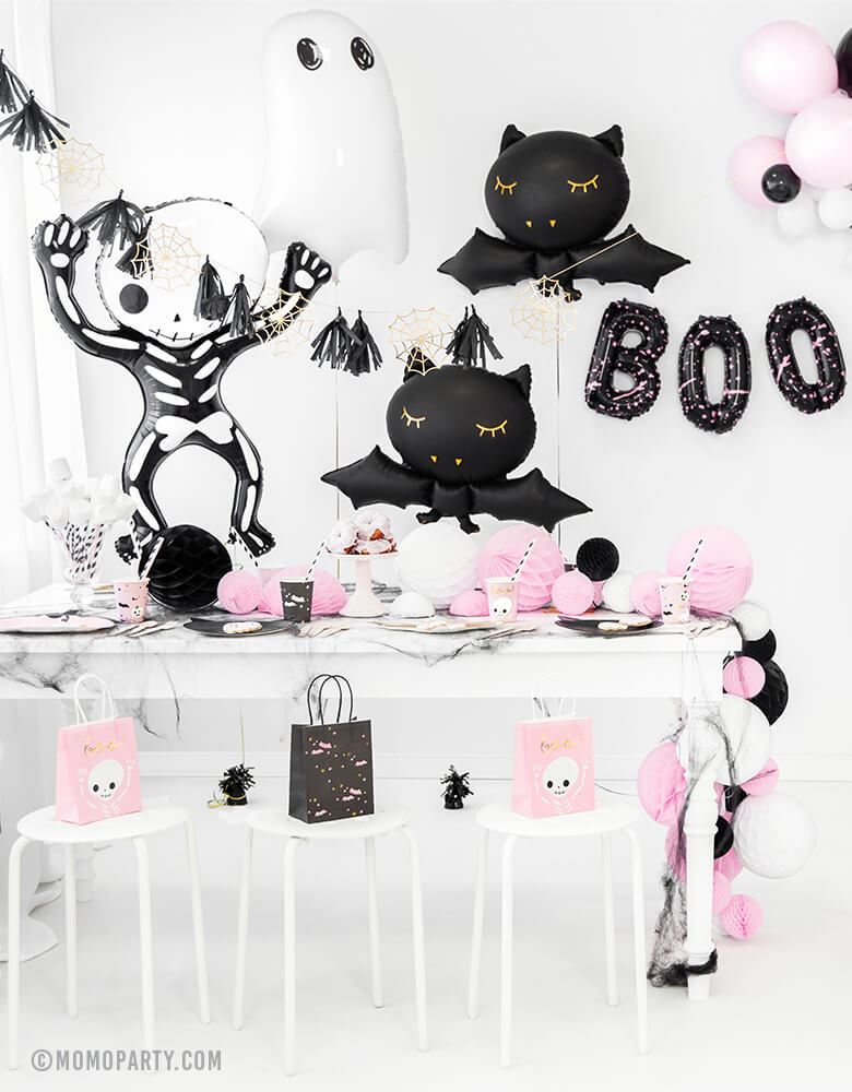 a Pink Halloween party decorated with Party Deco Halloween Skeleton shaped Foil Mylar Balloon, Halloween Ghost Foil Mylar Balloon, Black bat foil balloon, and golden spiderwebs and black tassels garland. BOO Letter Foil Balloon Set. there are pink ghost and black bats gift bags on each chair. These cute halloween balloons also perfect for Kid-Friendly modern spooky halloween party, trick-or-treating halloween party, nightmare before christmas party, witch themed party and all halloween related celebrations