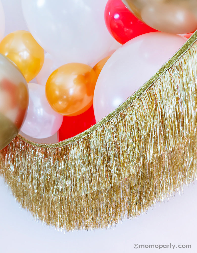 Momopartys Holiday party decoration idea Featuring Gold, Red, Pearl White, Coral, Pearl peach latex balloons with Meri Meri gold tinsel fringe garland