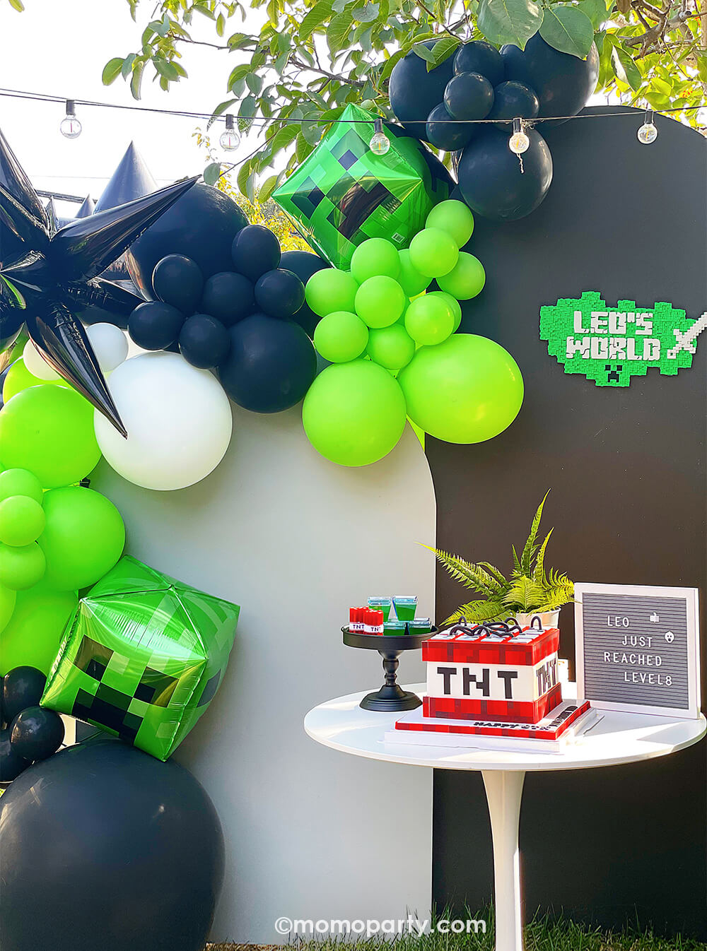 Minecraft themed Birthday Party Ideas by Momopartys. Featuring modern party Backdrop with minecraft themed color balloons in green, black, white, and creeper foil balloon, black starburst foil balloon. And TNT cake on the white round dessert table.