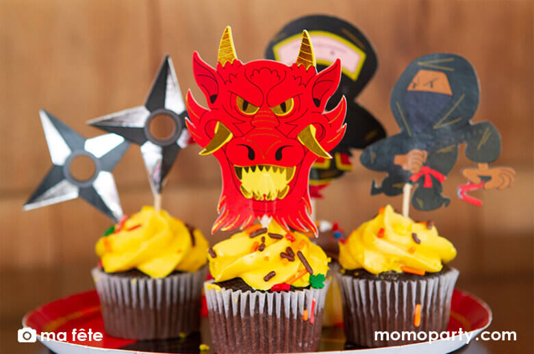 Chocolate cupcakes decorated with Momopartys's Ninja Cupcake Kit by Ma Fête. Featuring Ninjas, Dragon head, ninja darts designs. The toppers include gold foil details to give cupcakes an eye-catching finish. They are perfect for a Ninja themed birthday party