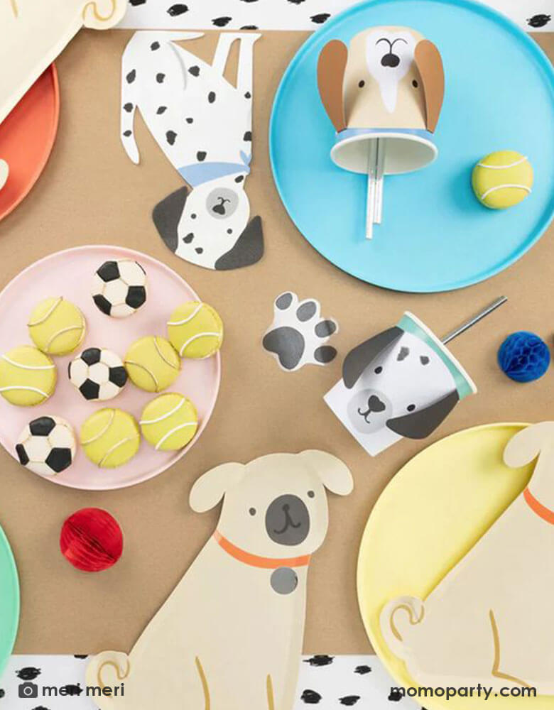 Momopartys kid's puppy dog themed birthday party table flat lay, decorated with a Pug Plate on a yellow round plate, Brown Puppy Cup with silver foil straws on sky blue colored plate, a Damatian Puppy Napkins , tennis ball macarons all on the black dots tablecloth, These modern and cute design party supplies from Meri Meri of Cat and Dog Collection,will make an Insta-perfect party table for your kid's puppy or dog themed birthday party.