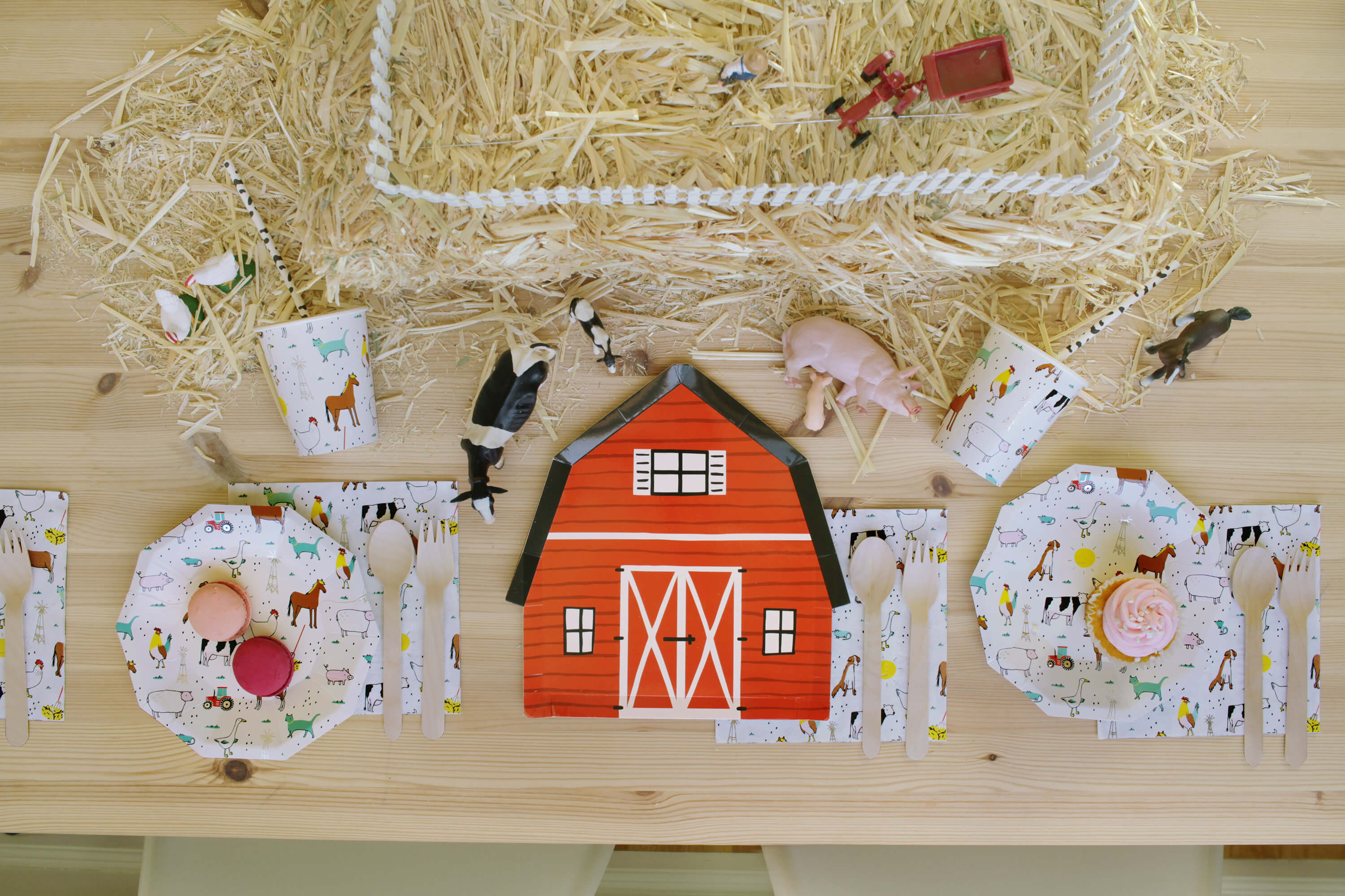 Barnyard Farm Themed Party for Kids, with a barnyard plates, farm animal plates, napkins, cups and sweets on top of a wooden textured dining table, table Styled by Momopartys
