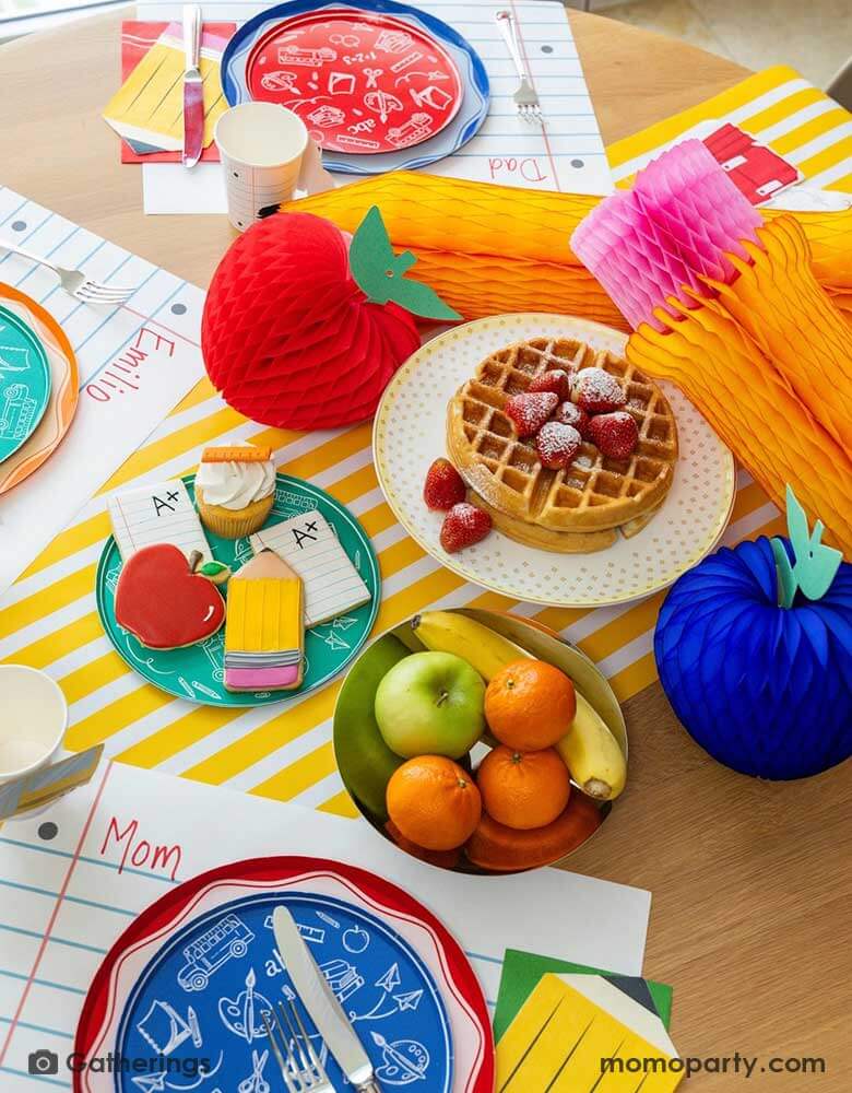 A festive back to school first day of school celebration party table setting featuring Momopartys's back to school themed party supplies including the No. 2 pencil patterned dinner plates, school day side plates with school supplies designs in different colors, and loose leaf paper placemat by Gatherings. With apple and pencil shaped honeycomb as the centerpiece, plus a plate of fruits school supply themed sugar cookies, makes a great inspo to celebrate the start of the new school year with kids!