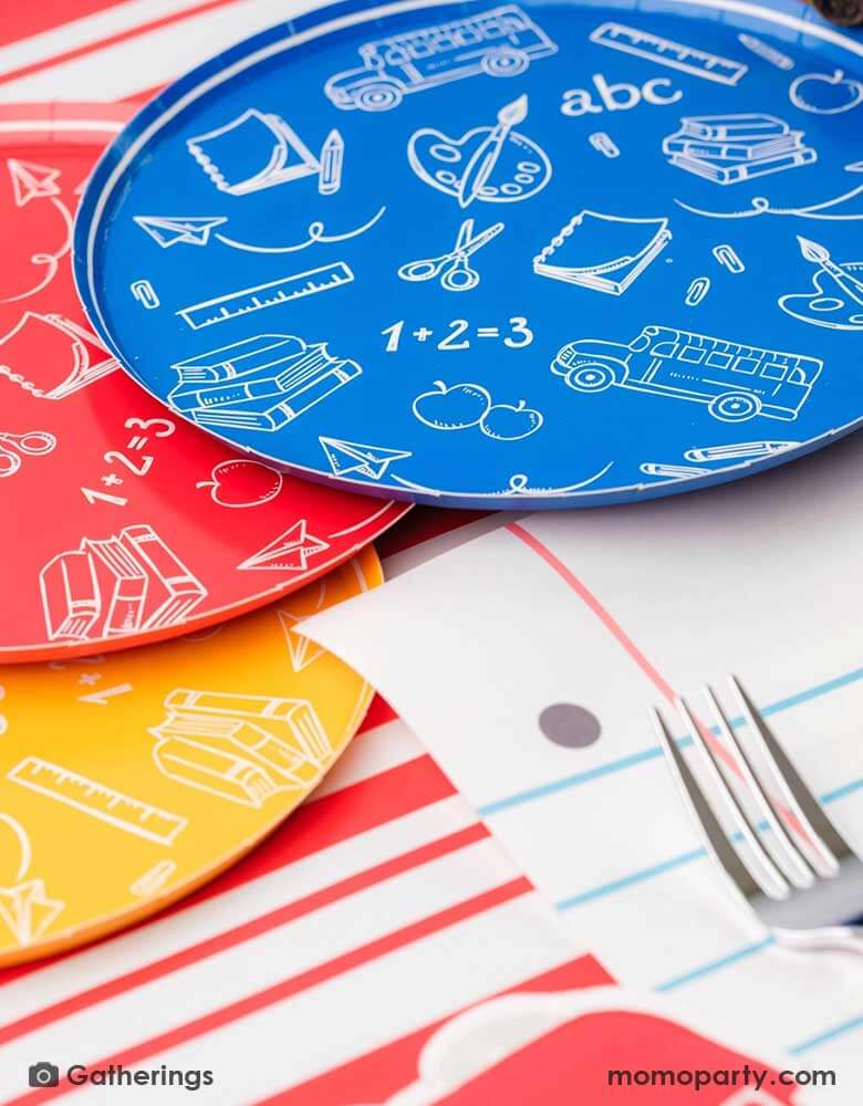 A close up of a back to school party featuring school themed party supplies from Momopartys including school day assorted side plates with school supply patterns in 4 colors of green, blue, red and yellow, with the No. 2 pencil patterned dinner plates and loose leaf paper placemats by Gatherings. A perfect place setting to celebration kid's or student's first day of schoo,