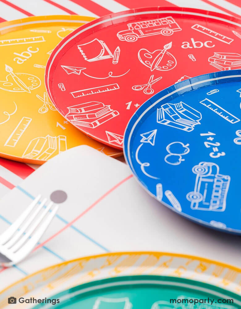 A close up of a back to school party featuring school themed party supplies from Momopartys including school day assorted side plates with school supply patterns in 4 colors of green, blue, red and yellow, with the No. 2 pencil patterned dinner plates and loose leaf paper placemats by Gatherings. A perfect place setting to celebration kid's or student's first day of schoo,