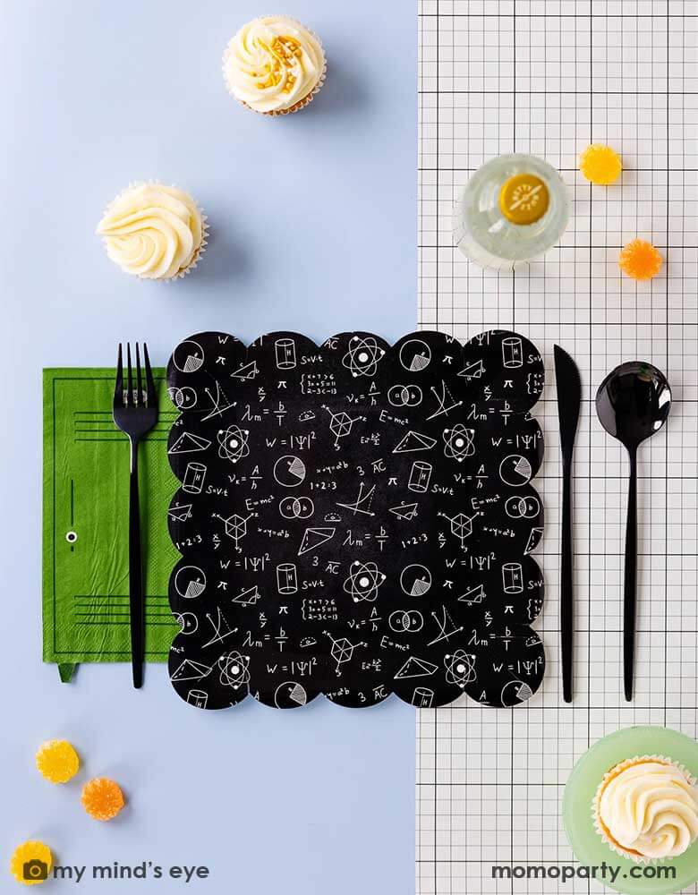 A modern back to school party placeset featuring Momopartys's school themed party supplies including the black equation plate, the green school locker shaped napkin, the back to school black and white grid table runner and some some black silverware, with some cupcakes and candies around this makes a simple and modern tablescape for a back to school or first day of school celebration.