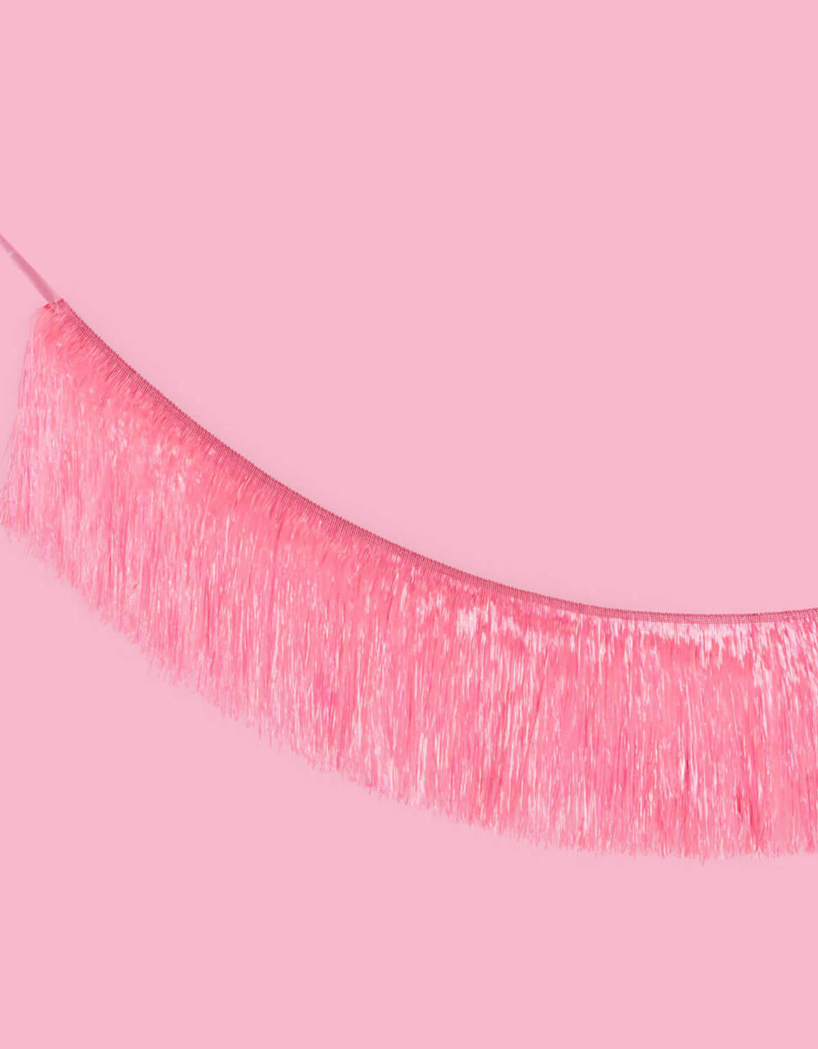 Close up shot of Momopartys's 5 ft Bright Pink Fringe Garland on a pink background.