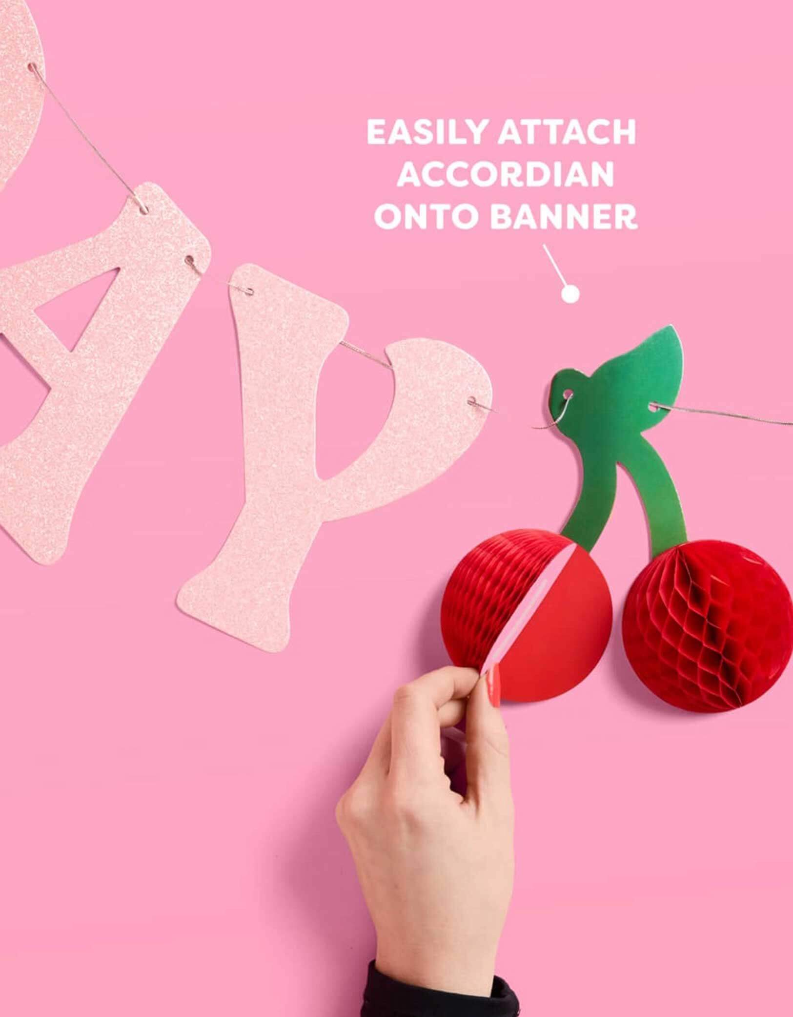 Momo Party's 4.5' cherry happy birthday banner with cherry honeycomb decoration on a pink background.