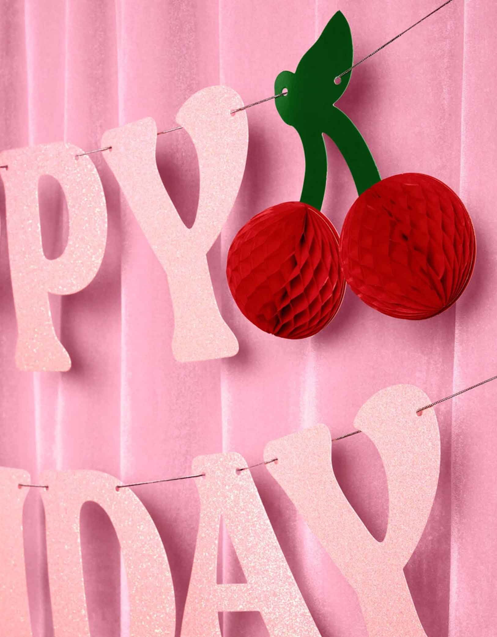 Momo Party's 4.5' cherry happy birthday banner hung against a pink curtain.