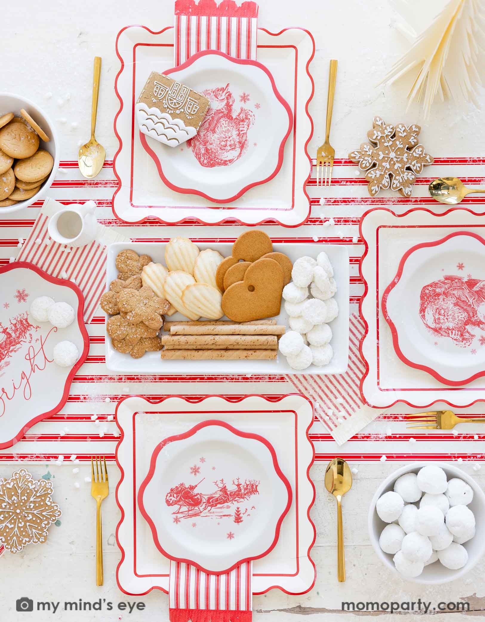 Christmas-themed table setting with red and white plates with Santa design, red striped napkins, cookies, and gold utensils on a matching red striped table runner from Momopartys.