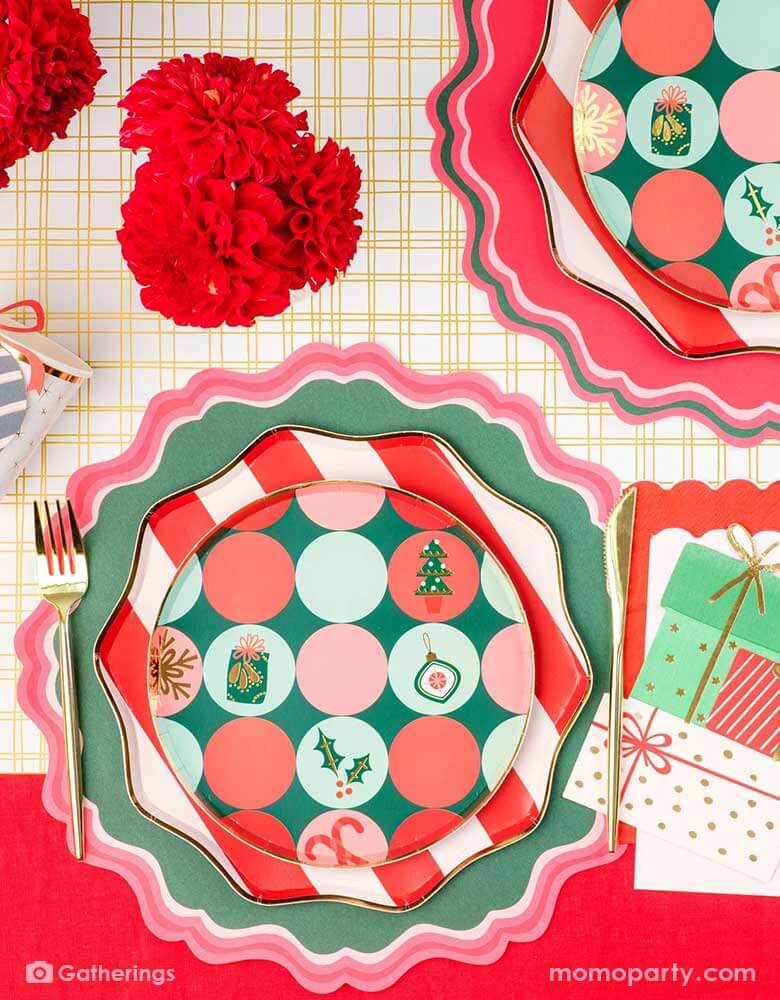 A festive Christmas party tablescape featuring Momopartys's Holiday tableware collection including red striped dinner plates and Christmas icon patterned side plates, with gifts shaped napkins and red and green placemats on the gold grid table runner, this makes a jolly table setting for this Holiday season.