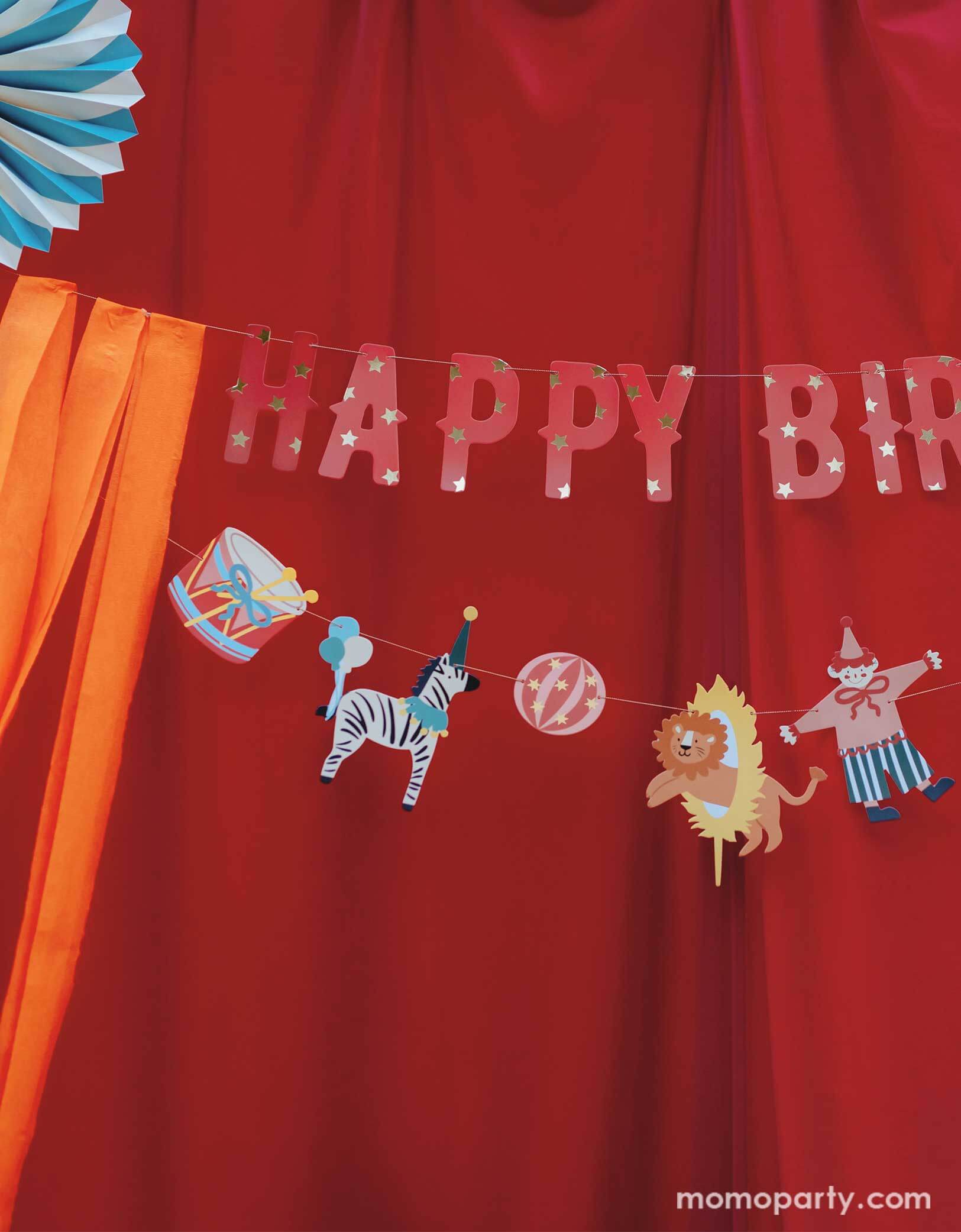 A vintage circus themed party backdrop with a red stage curtain decorated with Happy Birthday circus banner from Momopartys. Featuring fun and festive circus animals, bright orange streamers, and the classic "Happy Birthday" message, this banner will add a playful touch to any party. Bring the carnival to your birthday bash with this fun and colorful set!