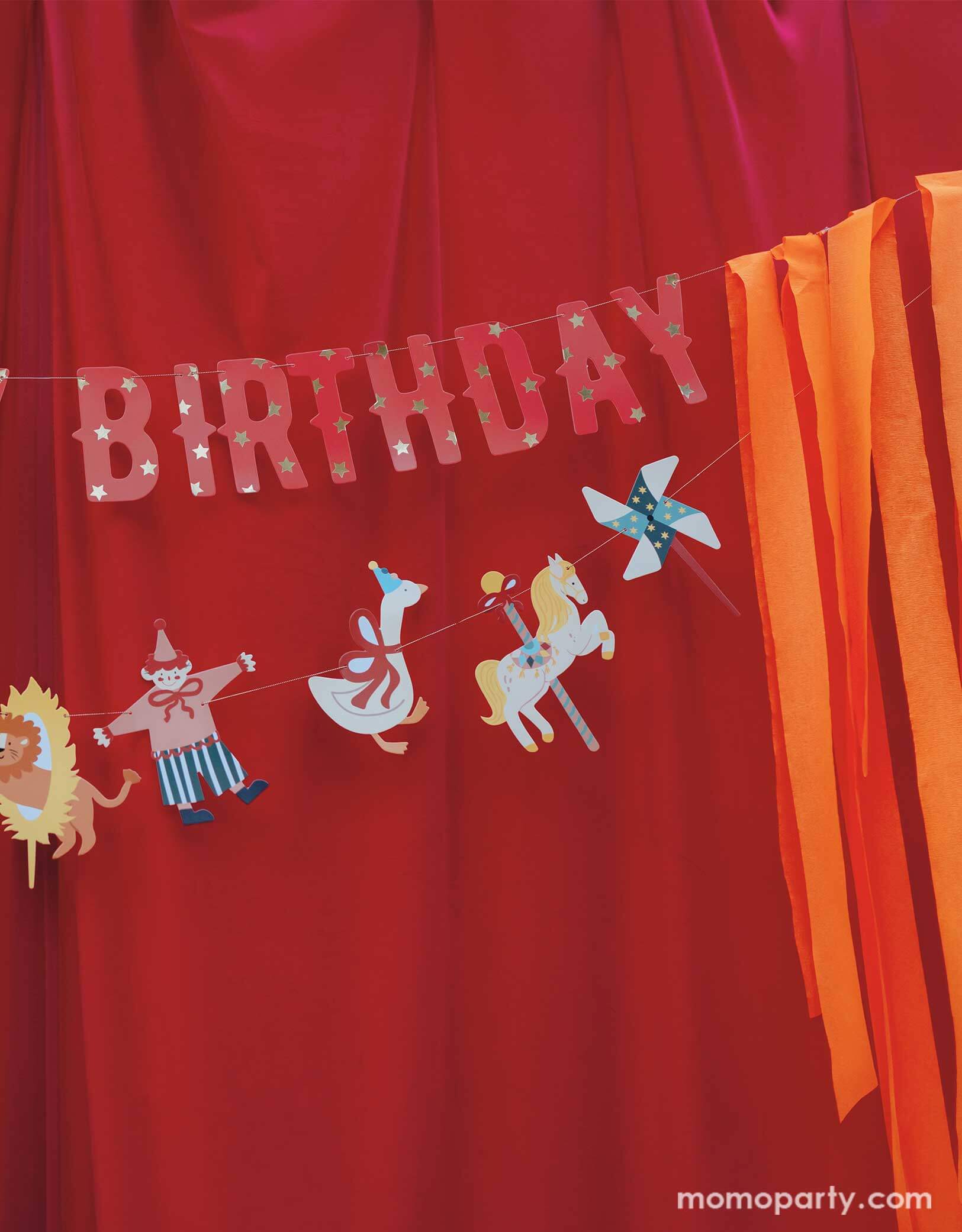 A vintage circus themed party backdrop with a red stage curtain decorated with Happy Birthday circus banner from Momopartys. Featuring fun and festive circus animals, bright orange streamers, and the classic "Happy Birthday" message, this banner will add a playful touch to any party. Bring the carnival to your birthday bash with this fun and colorful set!