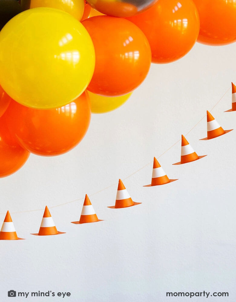 A kid's construction themed birthday party decoration featuring a balloon garland in classic construction colors of orange yellow and black,  adorned with Momopartys's 6f 3D construction cone paper banner, making this a perfect inspo for boy's construction themed birthday party decoration.