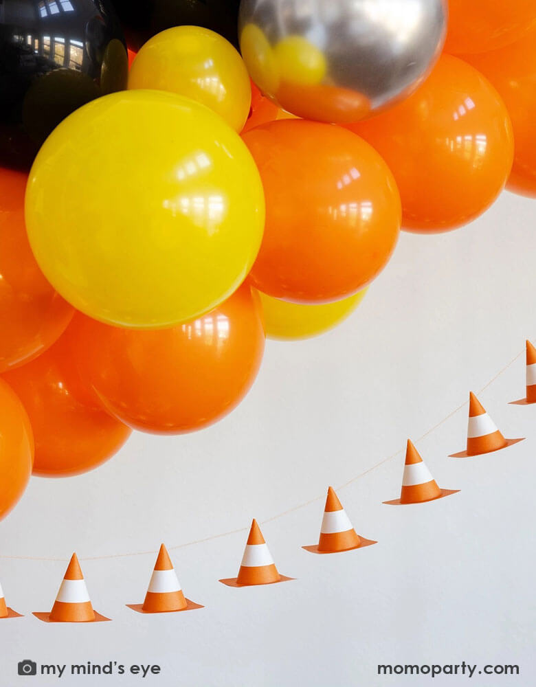 A kid's construction themed birthday party decoration featuring a balloon garland in classic construction colors of orange yellow, sliver and black,  adorned with Momopartys's 6f 3D construction cone paper banner, making this a perfect inspo for boy's construction themed birthday party decoration.