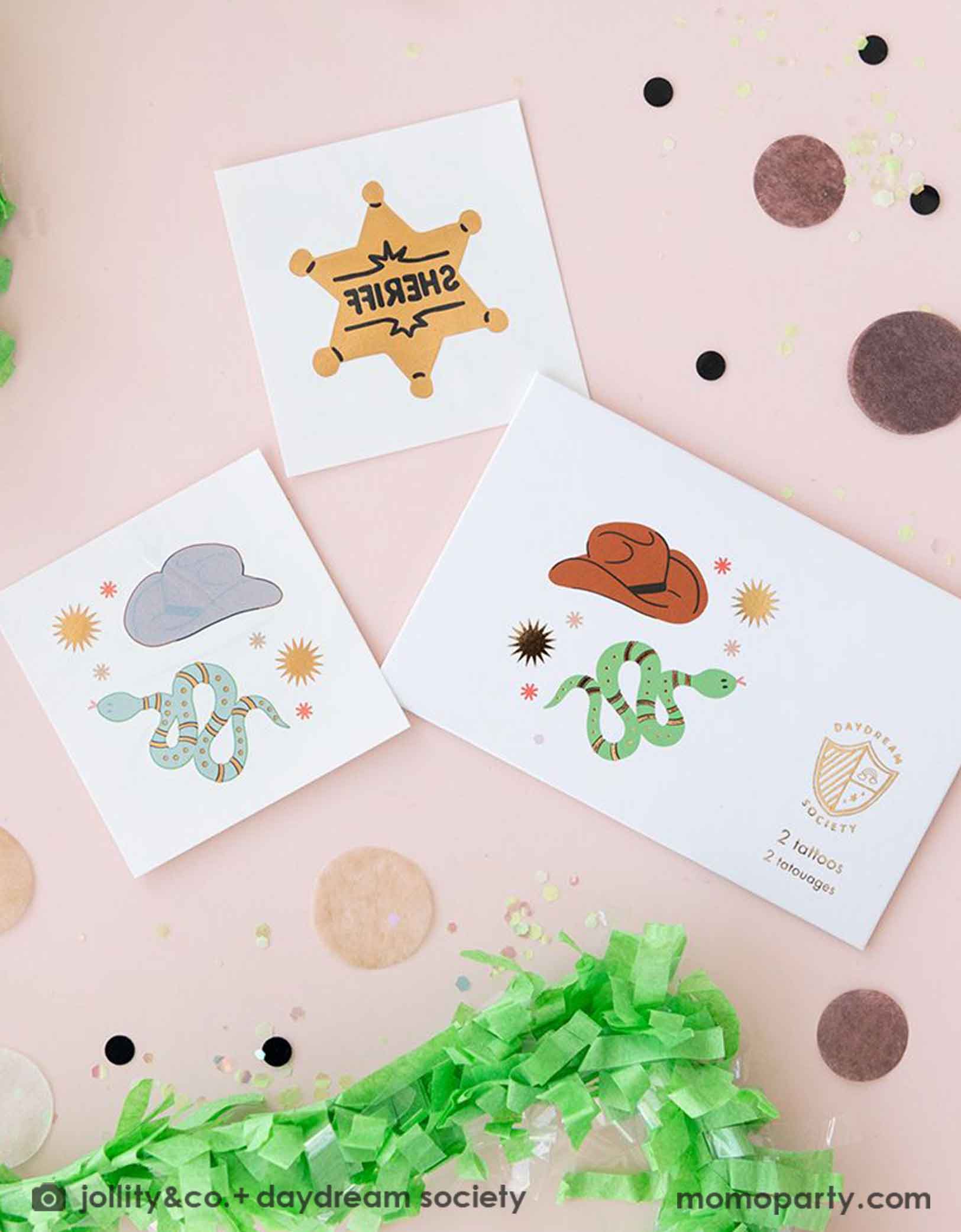 An overshot of Momopartys's Yeehaw Cowboy Temporary Tattoos by Daydream Society.  These temporary tattoos feature designs of a cowboy hat, snake, and sheriff badge in shiny gold foil. Around the temporary tattoo sheets there are some brown round confetti and some green streamers. They make perfect party favors for kid's Western or cowboy themed birthday celebration!