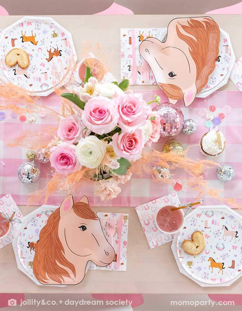 A cowgirl pony themed birthday party table featuring Momopartys's 9" x 11" pony shaped plates, cowgirl motif side plates and napkins by Daydream Society. In the middle of the party table there's a pink gingham patterned linen runner with disco ball decorations and pink flower bouquet , making this a perfect party table setting idea for a girly pony / western cowgirl themed celebration.