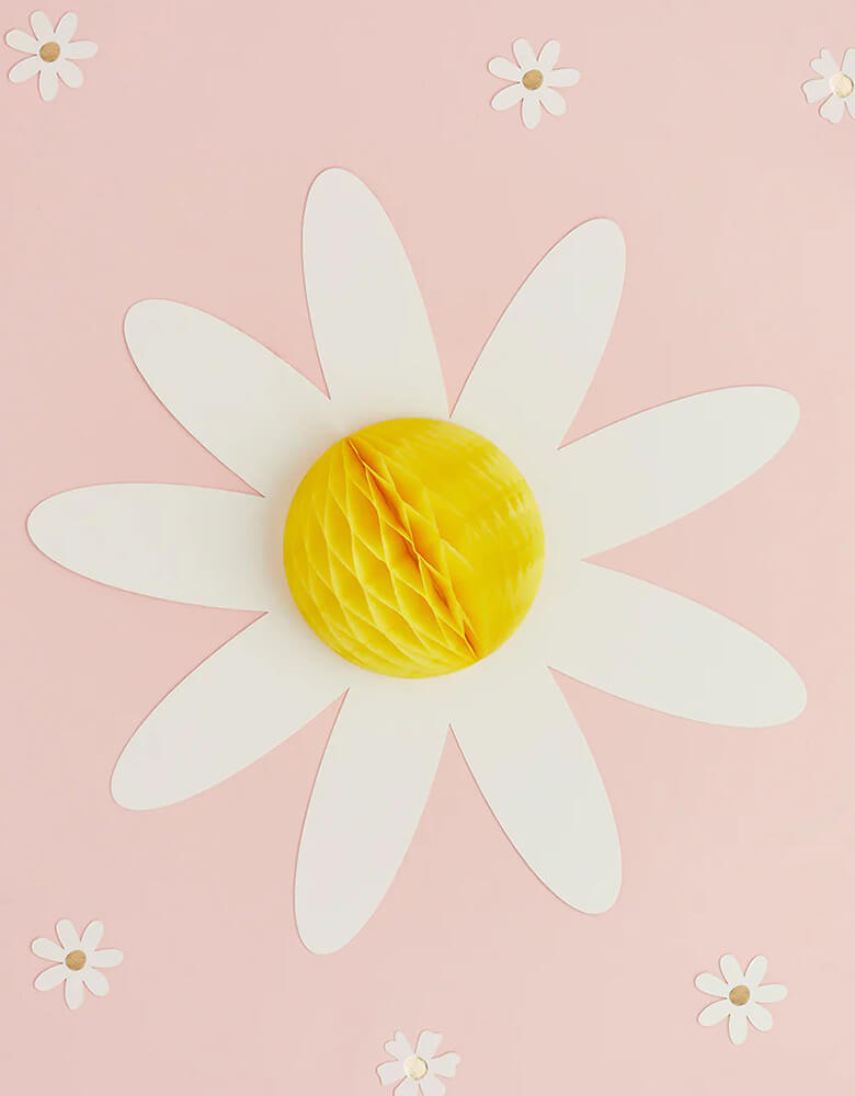A close up of Momopartys's 13" Daisy Honeycomb by Hooty Balloo surrounding with daisy confetti  Comes in a set of 3 honeycombs, the perfect honeycomb decorations for any birthday, bbq or mother's day celebration! Take any celebration from basic to breathtaking with these versatile honeycomb decorations!