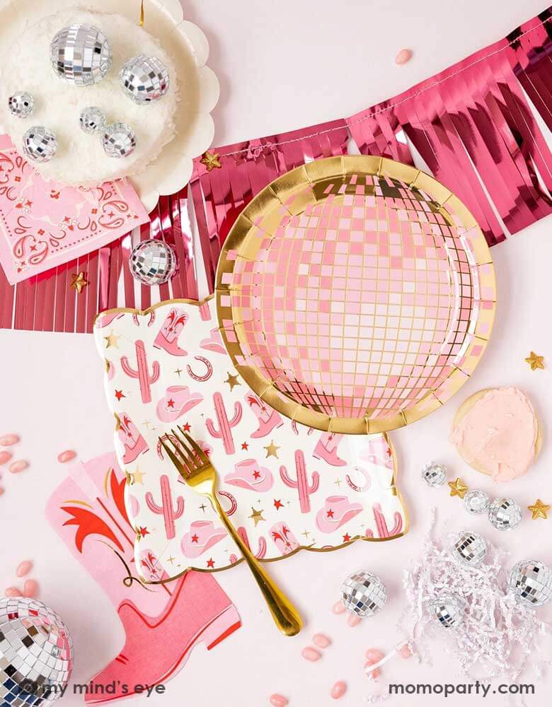 A cowgirl rodeo Western themed party table features pink cowgirl themed party supplies and decorations from Momopartys including pink cowgirl boot shaped napkins, pink disco ball shaped plates, pink bandana small napkins and pink foil fringe banner by My Mind's Eye, along with festive disco ball decorations and pink treats, this makes a perfect inspo for kid's cowgirl themed birthday party or a disco cowgirl "Let's Go Girls" themed bachelorette party celebration!
