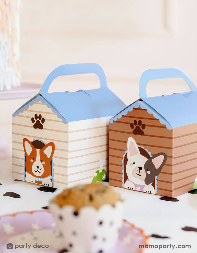 A kid's puppy dog theme party table featuring Momopartys's Dog House Party Boxes by Party Deco surrounded by dog themed party supplies including Dalmatian print tablecloth and cupcake wrappers. These adorable party favor boxes are perfect for goodies that will make any birthday party or kid's party a howling good time. These party boxes are a must-have for any canine celebration.