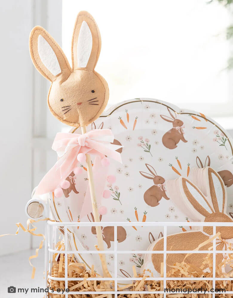 A close up of an Easter occasion bin filled with Momopartys's Easter themed tableware, treat bags and kid's gift, including the 9" x 9" scatter rabbit plates, rabbit shaped napkins, Easter bunny wand and carrot shaped treat bags by My Mind's Eye.